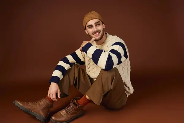 Handsome young man in a cozy, knitted outfit highlights his fashion sense while seated. — Stock Photo