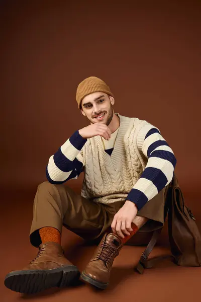 Ein stylischer junger Mann in Mütze posiert diesen Winter lässig in einem Atelier. — Stockfoto