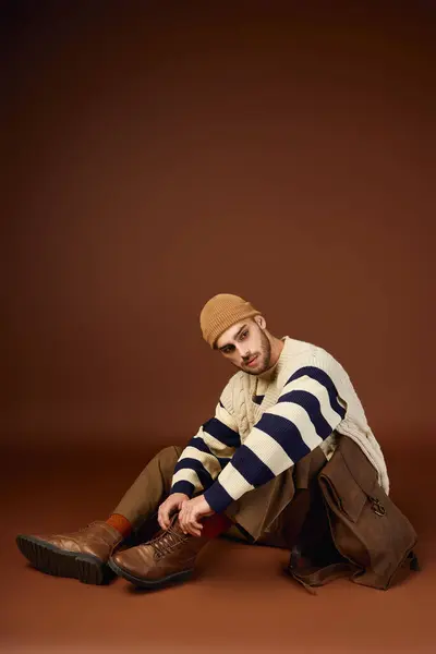 Un joven guapo muestra su sentido único de la moda mientras está sentado en un estudio. - foto de stock