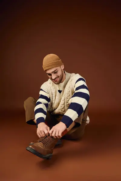 Handsome young man dons a fashionable winter outfit with a knitted beanie in a studio. — Stock Photo