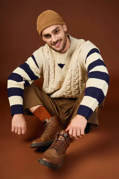 A handsome young man poses confidently in a trendy outfit and beanie, highlighting winter fashion. — Stock Photo