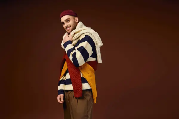 A young man models a trendy outfit featuring a stylish beanie and layered winter knits. — Stock Photo