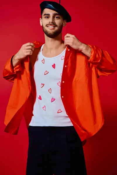 A young man with charm displays his unique fashion sense in a red-themed studio setting. — Stock Photo