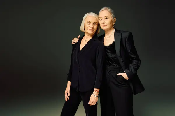 Two mature women stand closely together, exuding elegance and affection in their trendy attire. — стоковое фото