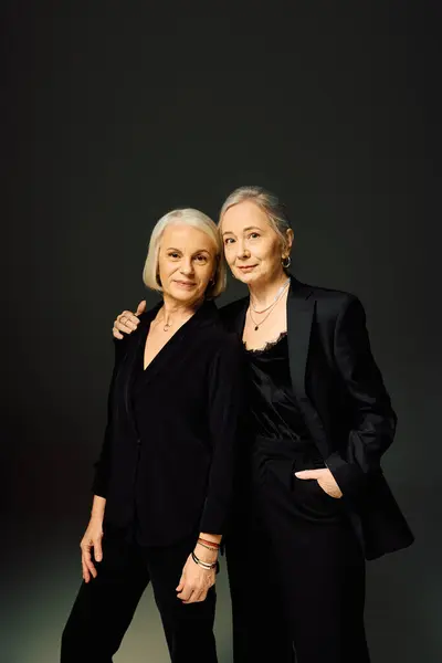 Two mature women dressed in fashionable attire embrace each other with love and confidence. — Stock Photo