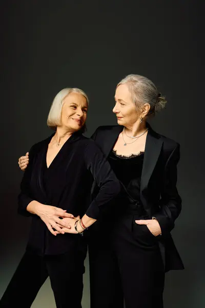 Two fashionable women express love and connection while posing gracefully in chic outfits. — Stock Photo