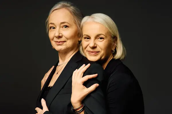 Two mature women share a moment of love and connection while showcasing their stylish outfits. — Stock Photo