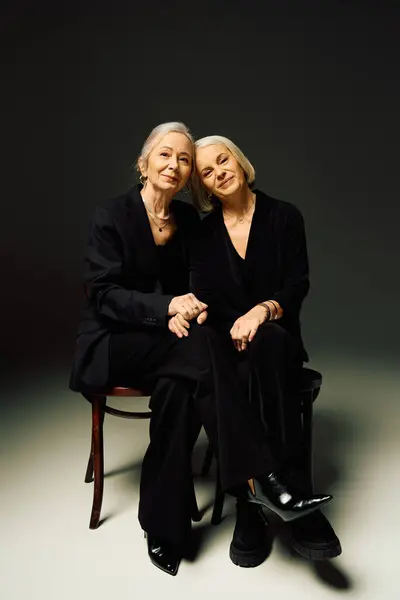 Two mature women comfortably seated together, exuding love and style in a warm, intimate atmosphere. — Stock Photo