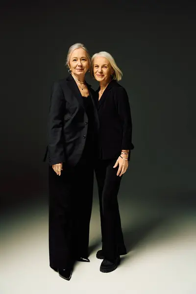 Two fashionable mature women stand together, exuding love and confidence in stylish attire. — Stock Photo