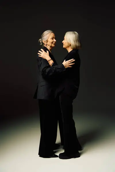 Two fashionable women share a warm embrace, radiating romance and confidence in a chic environment. — Stock Photo