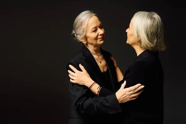 Two women standing close, embracing tenderly while dressed in fashionable attire, radiating love. — Stock Photo