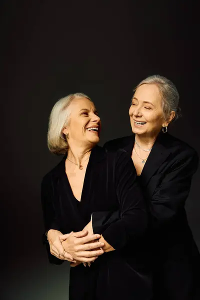 Two mature women embrace joyfully, showcasing love and connection in a chic atmosphere. — Stock Photo