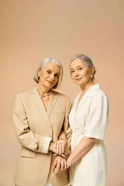 Two mature women in stylish outfits share a warm embrace, radiating love and confidence. — Stock Photo