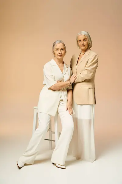 Two mature women elegantly pose together, embodying love and fashion in a cozy atmosphere. — Stock Photo