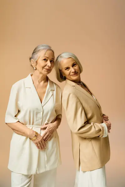 Two fashionable women share a loving moment while posing in a soft toned environment. — Stock Photo