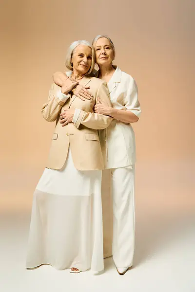 Two fashionable mature women share a tender embrace in a stylish and inviting environment. — Stock Photo