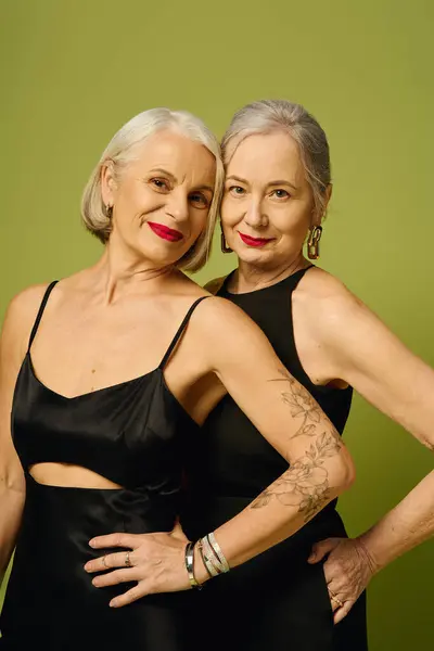 Two confident women in stylish outfits radiate love and elegance against a bright green backdrop. — Foto stock