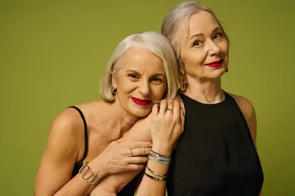 Two stylish women share a tender moment, showcasing their love against a vibrant green backdrop. — Stock Photo