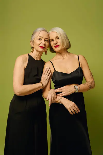 Two stylish mature women showcase their romance and confidence in a bold green backdrop. — Stock Photo