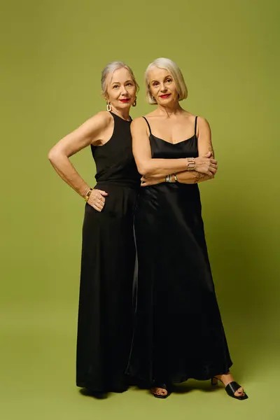 Two mature women dressed in elegant black attire showcase their fashionable style and deep bond. — Stock Photo