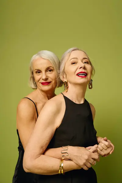 Two mature women celebrate love and romance in a fashionable embrace with trendy outfits. — Stock Photo