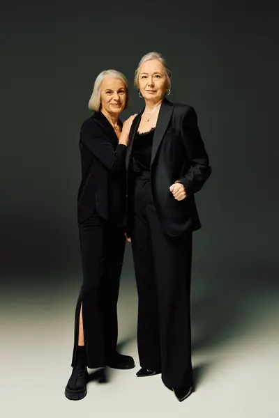 Two elegant women embrace each other warmly in a modern fashion studio, showcasing true romance. — Stock Photo