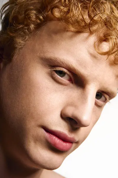 Young man with curly hair showcases a trendy style, exuding confidence and charisma indoors. — Stock Photo