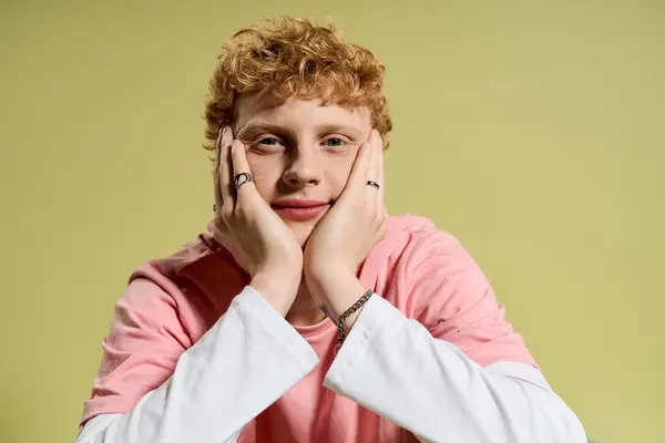 Un jeune homme à la mode aux cheveux bouclés repose son menton sur ses mains, respirant confiance et style. — Photo de stock