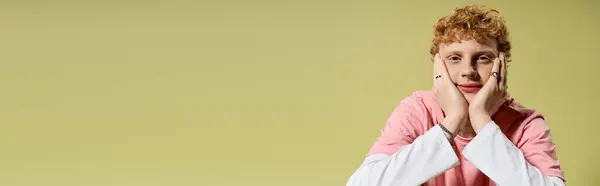Young man sports a fashionable outfit, resting his chin on his hands, and smiles playfully. — Stock Photo