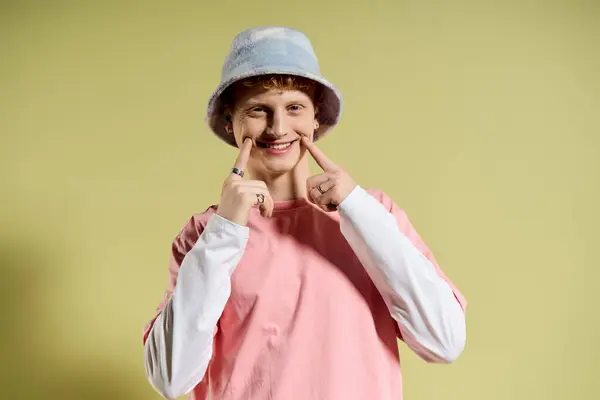 Stylish young man with a playful grin wearing a bucket hat and colorful attire, radiating joy. — Stock Photo