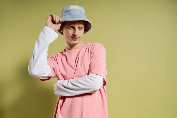 A handsome young man sports a fashionable bucket hat and a pink shirt while showcasing confidence. — Stock Photo