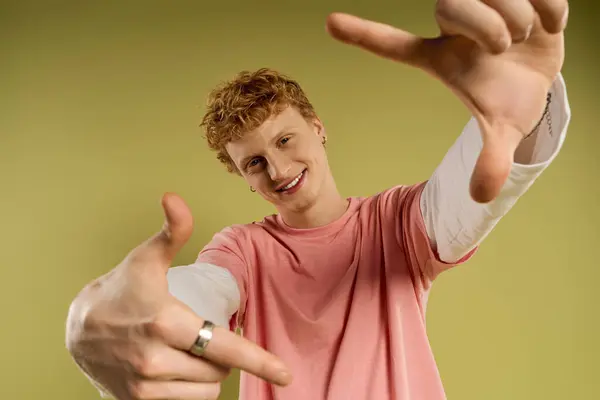 A fashionable young man with curly hair showcases his playful side against a vibrant backdrop. — Stock Photo