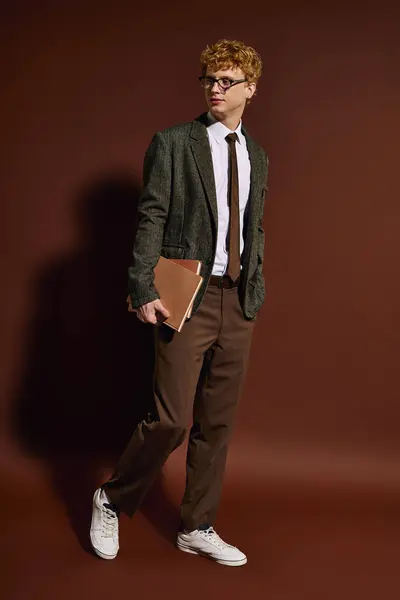 Confident young man in trendy outfit stands with a book, showcasing his modern style and poise. — Stock Photo