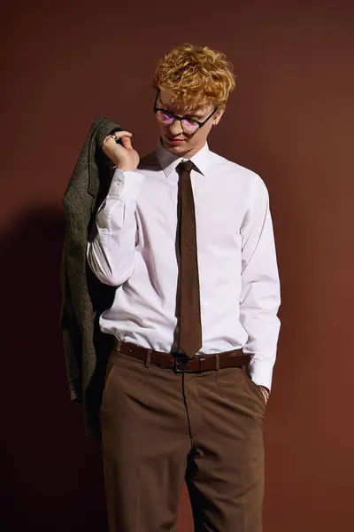 A stylish young man confidently poses with a jacket over his shoulder, displaying modern fashion. — Stock Photo