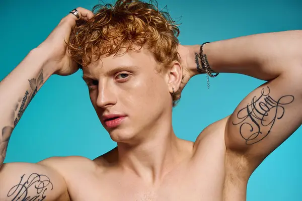 A fashionable young man poses confidently with tattoos visible, highlighting his stylish demeanor. — Stock Photo