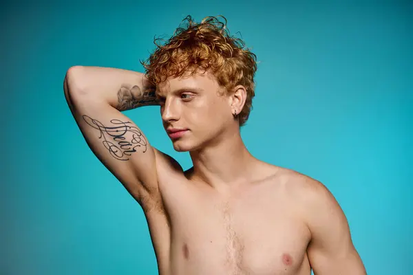 Confident young man showcases his trendy look and tattoo under bright blue lights. — Stock Photo