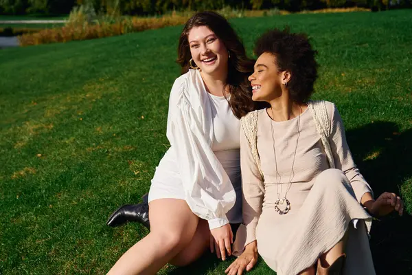 Two fashionable friends enjoy a sunny day in the park, radiating joy and confidence together. — Stock Photo