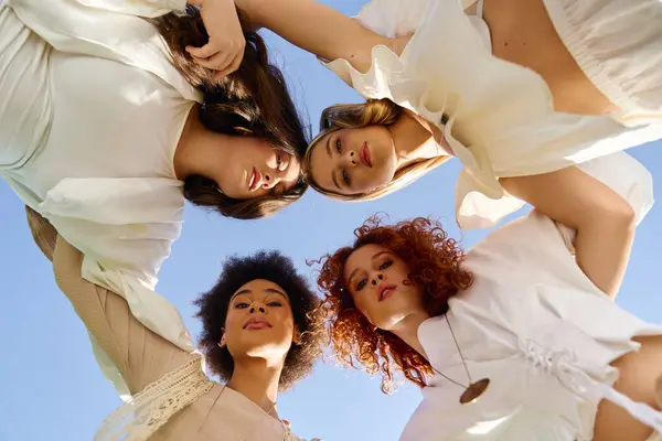 Four stylish women gather outdoors, showcasing fashion and confidence against a clear sky. — Stock Photo