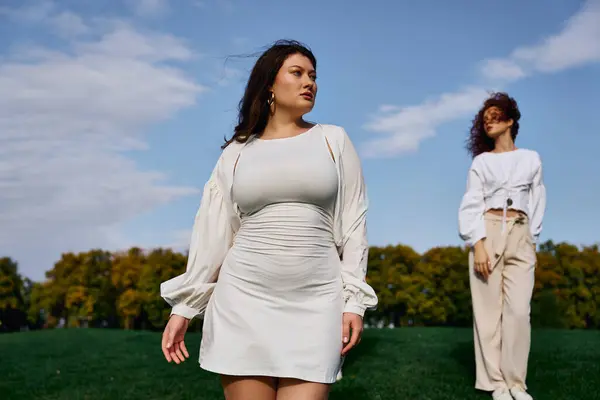 Two fashionable women explore a sunny park, showcasing trendy spring outfits and self assurance. — Stock Photo