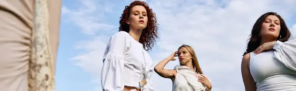 Three fashionable women showcase their stylish outfits against a beautiful spring backdrop. — Stock Photo