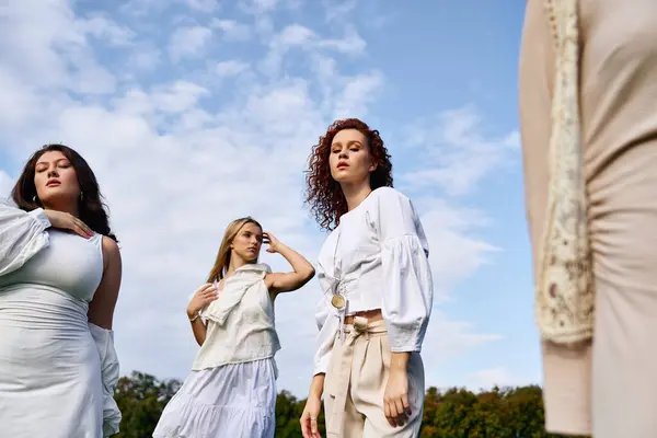 Three confident females showcase chic spring fashion amid a beautiful natural landscape. — Stock Photo