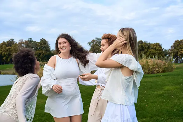 Four confident young women enjoy their time together, exuding stylish grace in a beautiful park. — Stock Photo