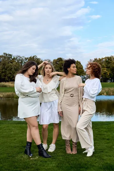 Four stylish women flaunt their unique spring looks in a sunny park, radiating confidence. — Stock Photo