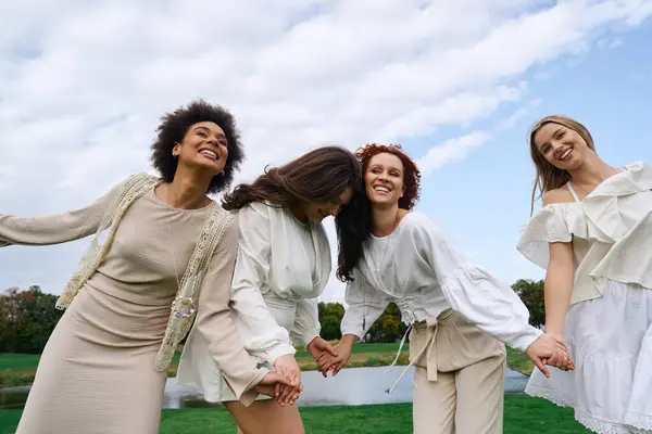 Four fashionable women are sharing laughter and connection while enjoying a sunny day outdoors. — Stock Photo