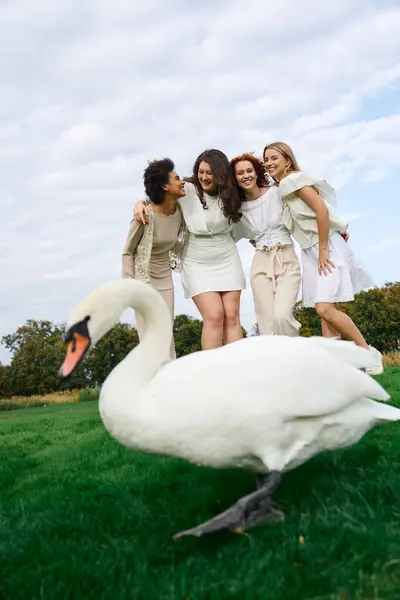 Four fashionable friends enjoy a fun moment outdoors while a graceful swan adds charm to the scene. — Stock Photo