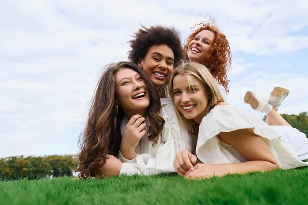 A group of stylish women shares a joyful moment on a sunny spring day, laughing together in nature. — Stock Photo