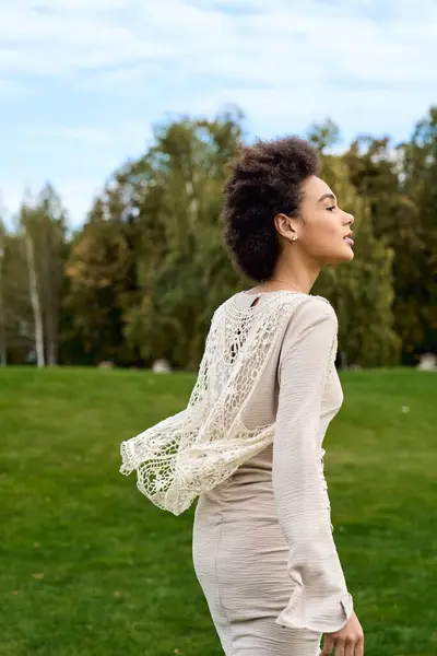 Confident female walks gracefully through a vibrant park, showcasing a chic spring outfit. — Stock Photo