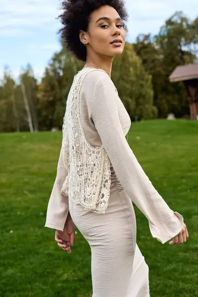 Fashionable female confidently strolls through a vibrant park, showcasing her unique spring style. — Stock Photo