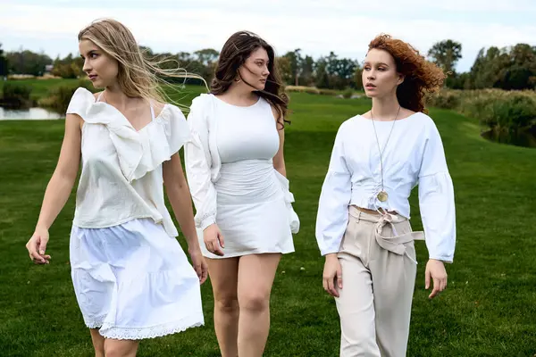 Three fashionable women showcase their chic outfits while enjoying a sunny day in a spring park. — Stock Photo