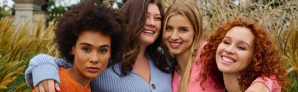 Four fashionable friends exude confidence while enjoying a sunny spring day in a beautiful park. — Stock Photo